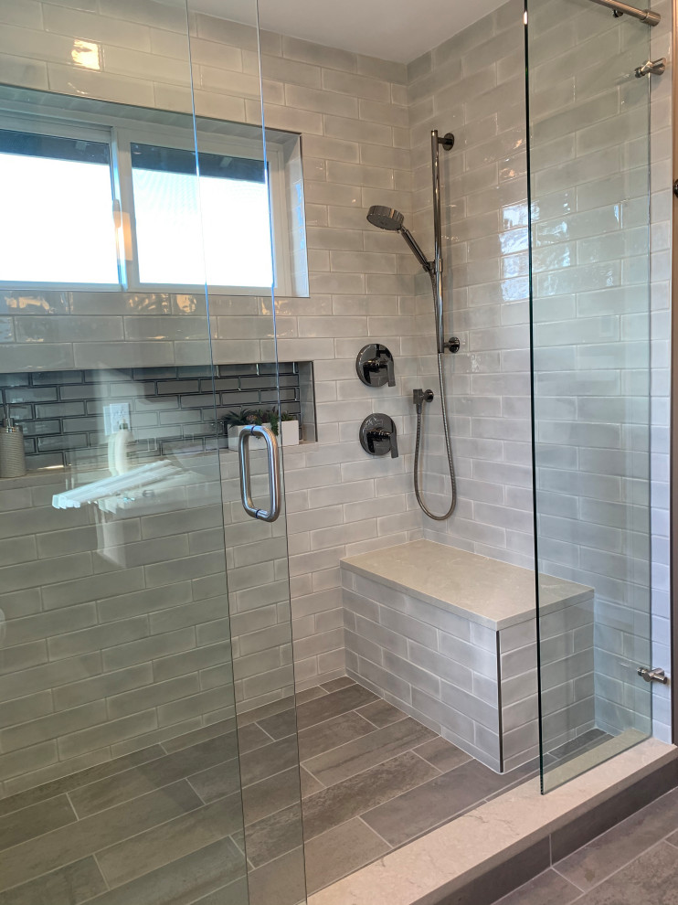 Medium sized modern ensuite bathroom with flat-panel cabinets, black cabinets, an alcove shower, a two-piece toilet, grey tiles, glass tiles, grey walls, wood-effect flooring, a vessel sink, engineered stone worktops, grey floors, a sliding door, white worktops, a wall niche, a shower bench, double sinks and a floating vanity unit.