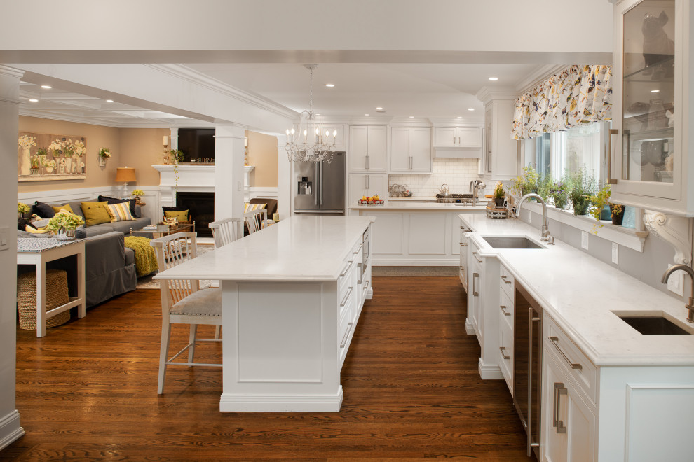 Inspiration for a large transitional single-wall dark wood floor and brown floor open concept kitchen remodel in New York with an undermount sink, shaker cabinets, white cabinets, marble countertops, stainless steel appliances, two islands and white countertops