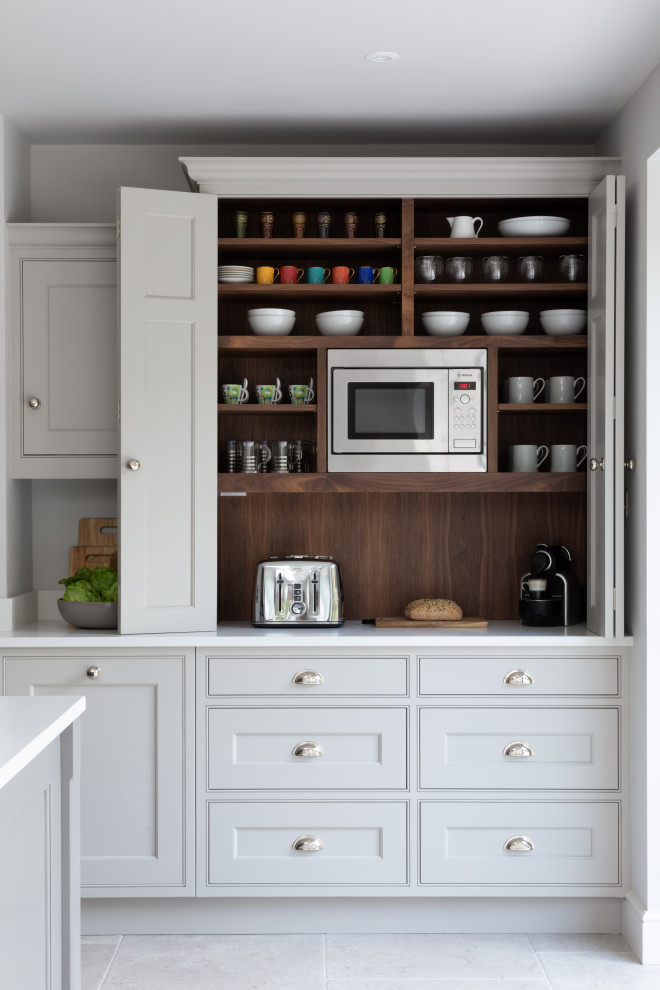 Inspiration for a large classic grey and white l-shaped open plan kitchen in Surrey with a built-in sink, shaker cabinets, grey cabinets, quartz worktops, metallic splashback, mirror splashback, stainless steel appliances, limestone flooring, an island, grey floors, white worktops and exposed beams.