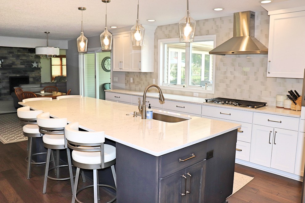 Inspiration for a transitional l-shaped medium tone wood floor and brown floor kitchen pantry remodel in Cedar Rapids with an undermount sink, recessed-panel cabinets, white cabinets, quartzite countertops, gray backsplash, porcelain backsplash, stainless steel appliances, an island and white countertops