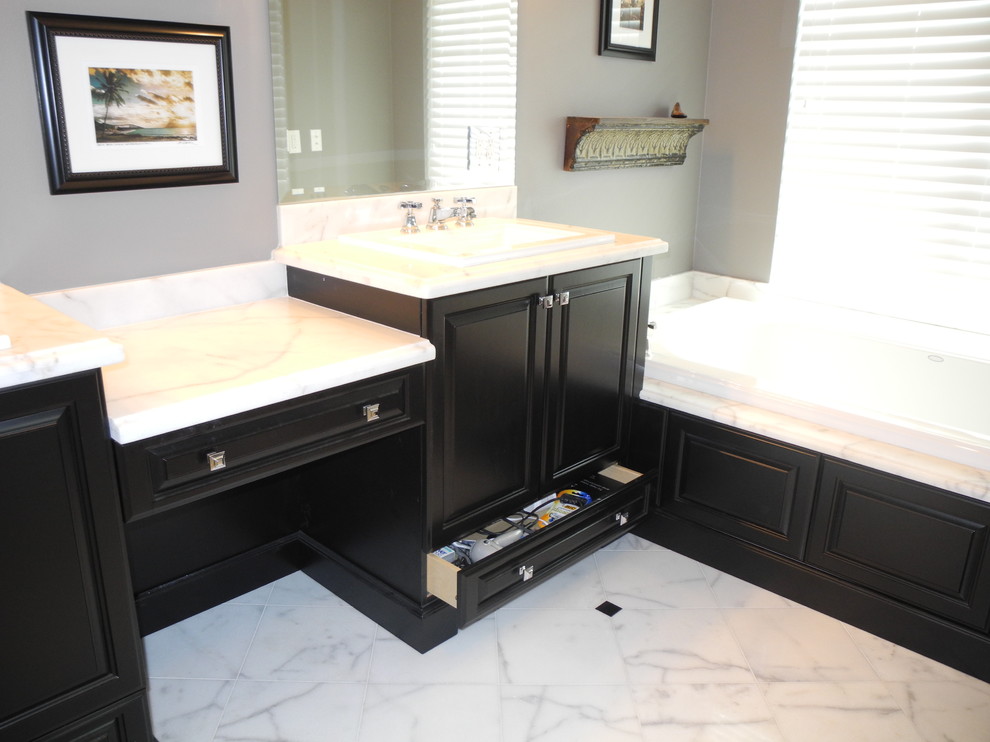 This is an example of a mid-sized traditional master bathroom in Miami with raised-panel cabinets, black cabinets, a shower/bathtub combo, grey walls, marble floors and a drop-in sink.