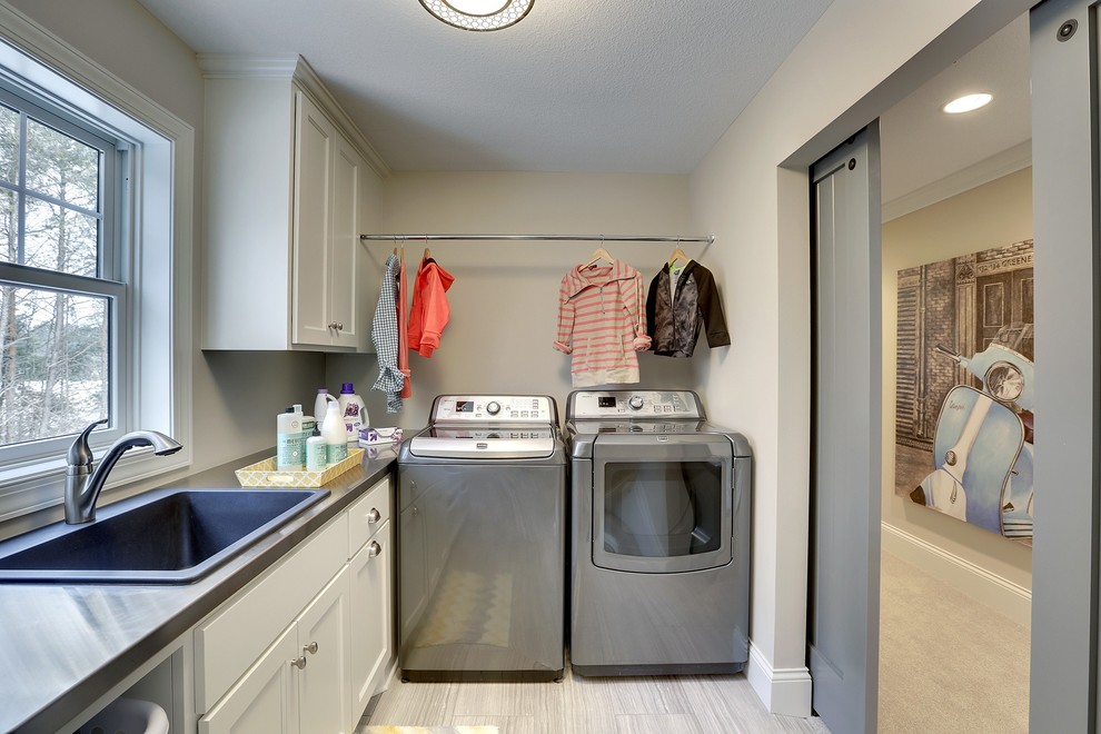 Design ideas for a large transitional l-shaped dedicated laundry room in Minneapolis with a drop-in sink, shaker cabinets, white cabinets, laminate benchtops, beige walls, ceramic floors and a side-by-side washer and dryer.