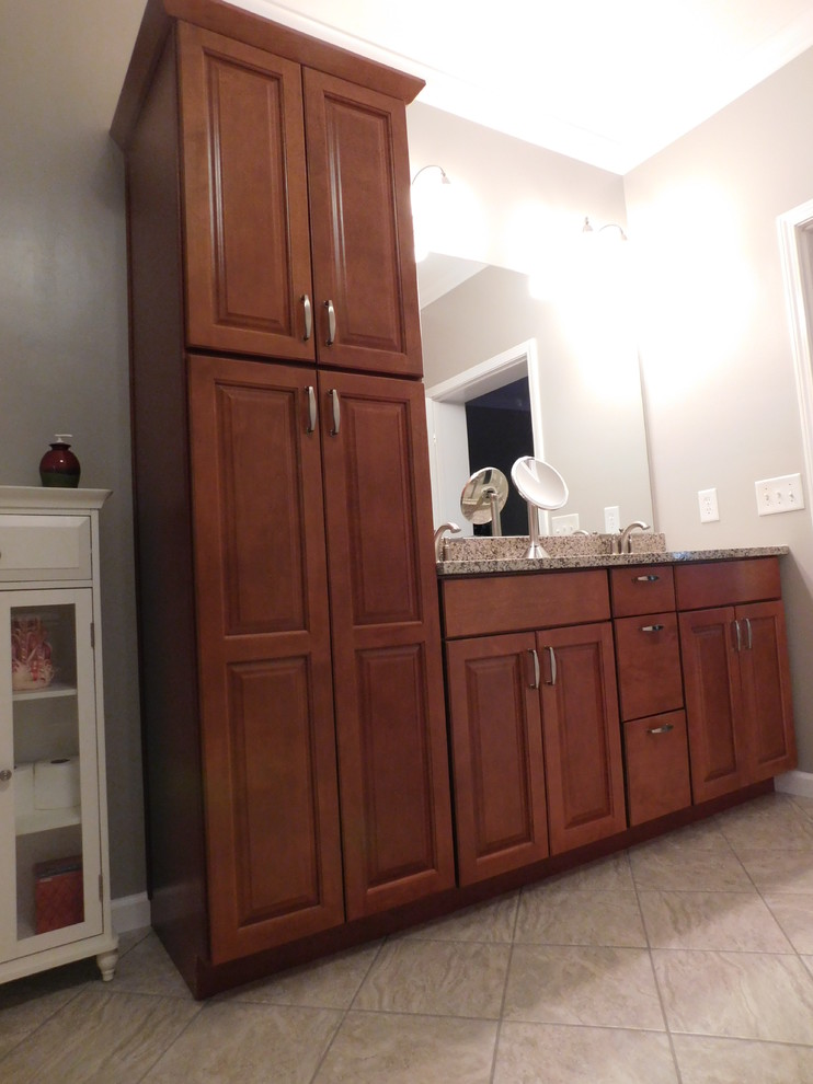Inspiration for a large transitional master gray tile and ceramic tile ceramic tile corner bathtub remodel with raised-panel cabinets, medium tone wood cabinets, a two-piece toilet, beige walls, an undermount sink and granite countertops