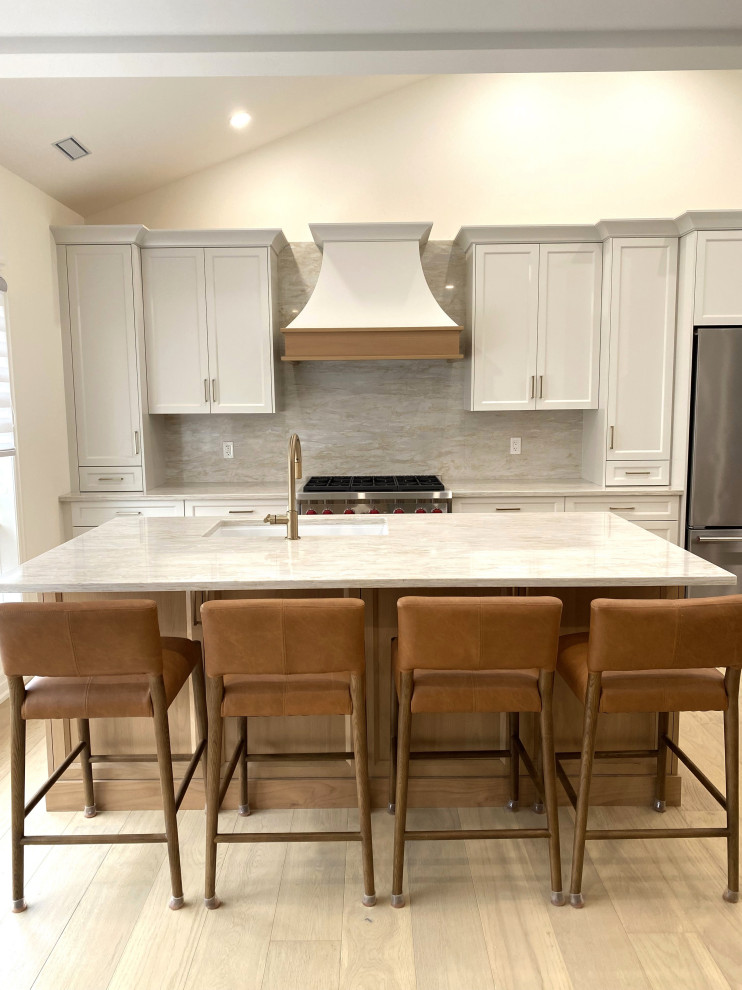 Open concept kitchen - small transitional galley light wood floor and vaulted ceiling open concept kitchen idea in Toronto with an undermount sink, recessed-panel cabinets, white cabinets, quartz countertops, quartz backsplash and stainless steel appliances