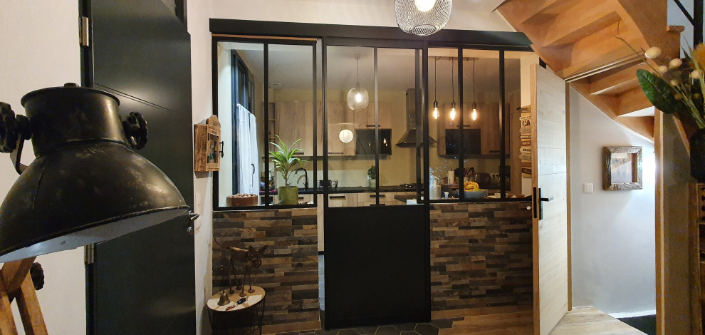 Photo of a mid-sized industrial l-shaped open plan kitchen in Paris with an undermount sink, shaker cabinets, light wood cabinets, laminate benchtops, stainless steel appliances, cement tiles, no island, grey floor and black benchtop.