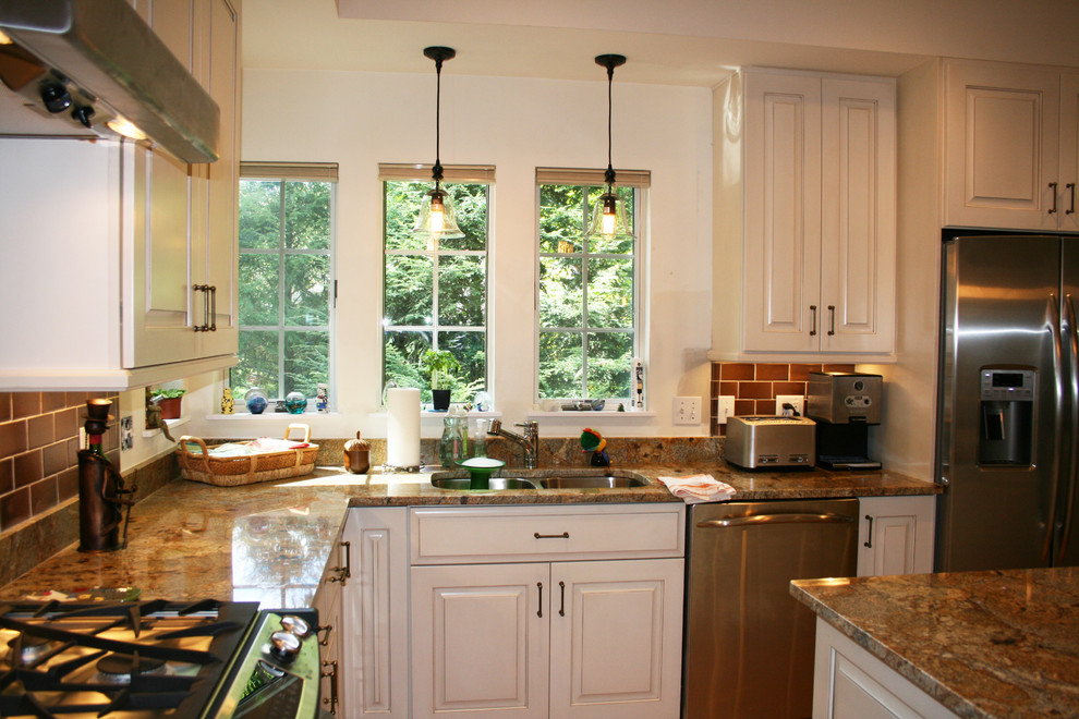 Eat-in kitchen - mid-sized transitional u-shaped medium tone wood floor eat-in kitchen idea with raised-panel cabinets, white cabinets, granite countertops, brown backsplash, subway tile backsplash, stainless steel appliances, an island and a double-bowl sink
