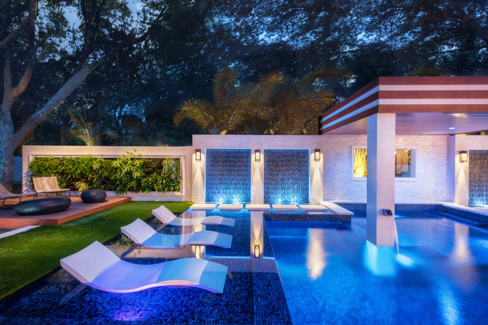 Foto de piscina infinita contemporánea grande a medida en patio trasero con privacidad y suelo de baldosas