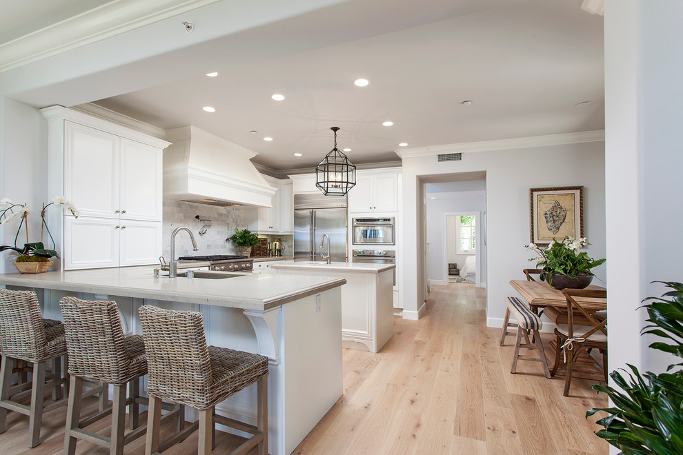 This is an example of a large beach style u-shaped eat-in kitchen in Other with white cabinets and with island.