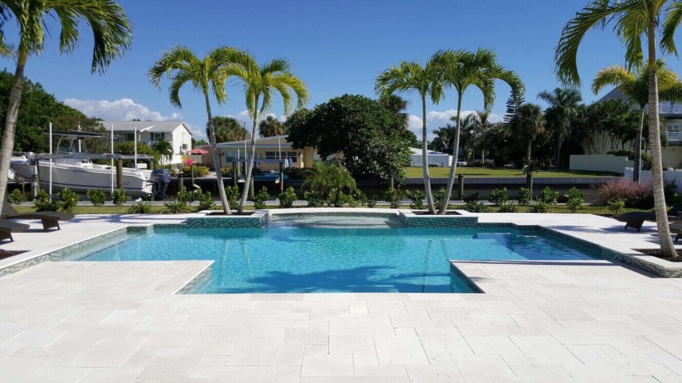Example of a large island style backyard tile and custom-shaped lap hot tub design in Miami
