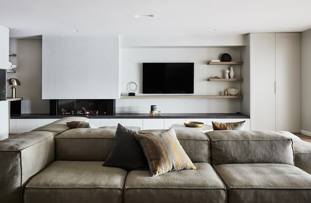 Design ideas for a large contemporary open concept family room in Sydney with a game room, grey walls, medium hardwood floors, a ribbon fireplace, a tile fireplace surround and a wall-mounted tv.