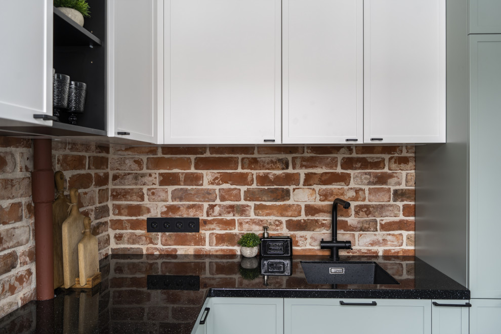Exemple d'une petite cuisine américaine grise et blanche tendance en L avec un évier 1 bac, des portes de placard turquoises, une crédence rouge, une crédence en brique, un électroménager noir, un sol blanc et plan de travail noir.