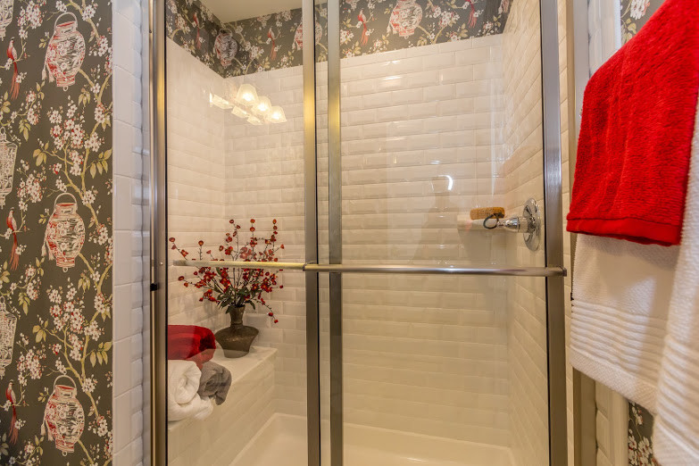 Transitional master white tile and subway tile ceramic tile and gray floor doorless shower photo with recessed-panel cabinets, dark wood cabinets, a one-piece toilet, multicolored walls, an integrated sink and solid surface countertops