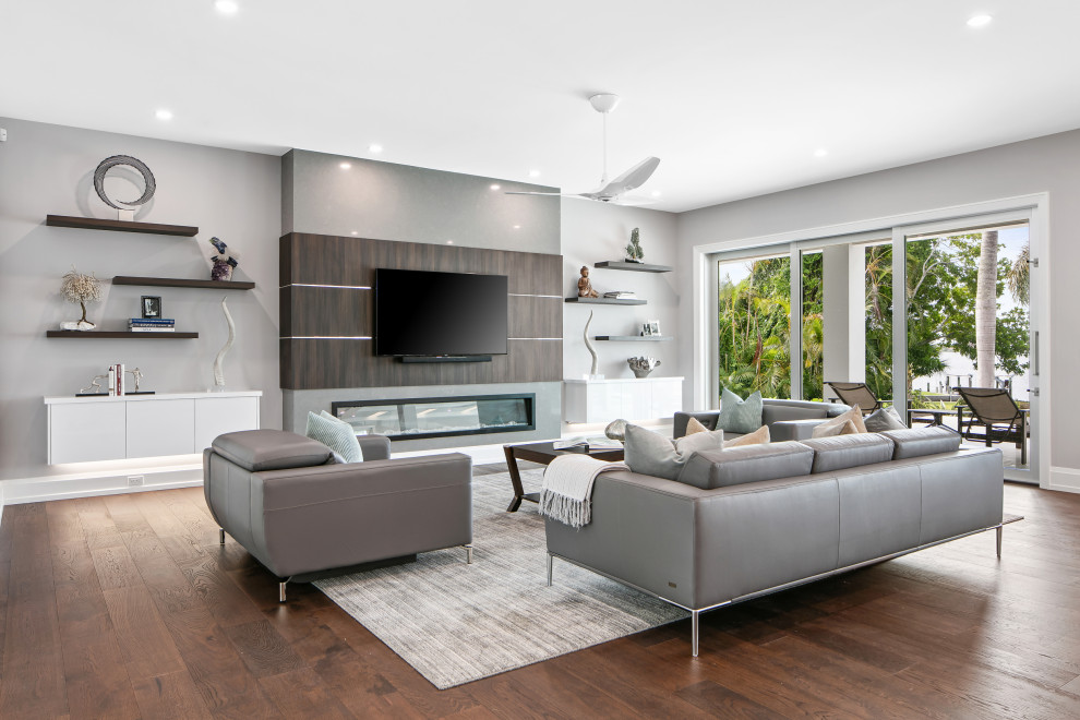 Inspiration for an expansive contemporary formal open concept living room in Tampa with grey walls, dark hardwood floors, a ribbon fireplace, a stone fireplace surround, a wall-mounted tv, brown floor and wallpaper.