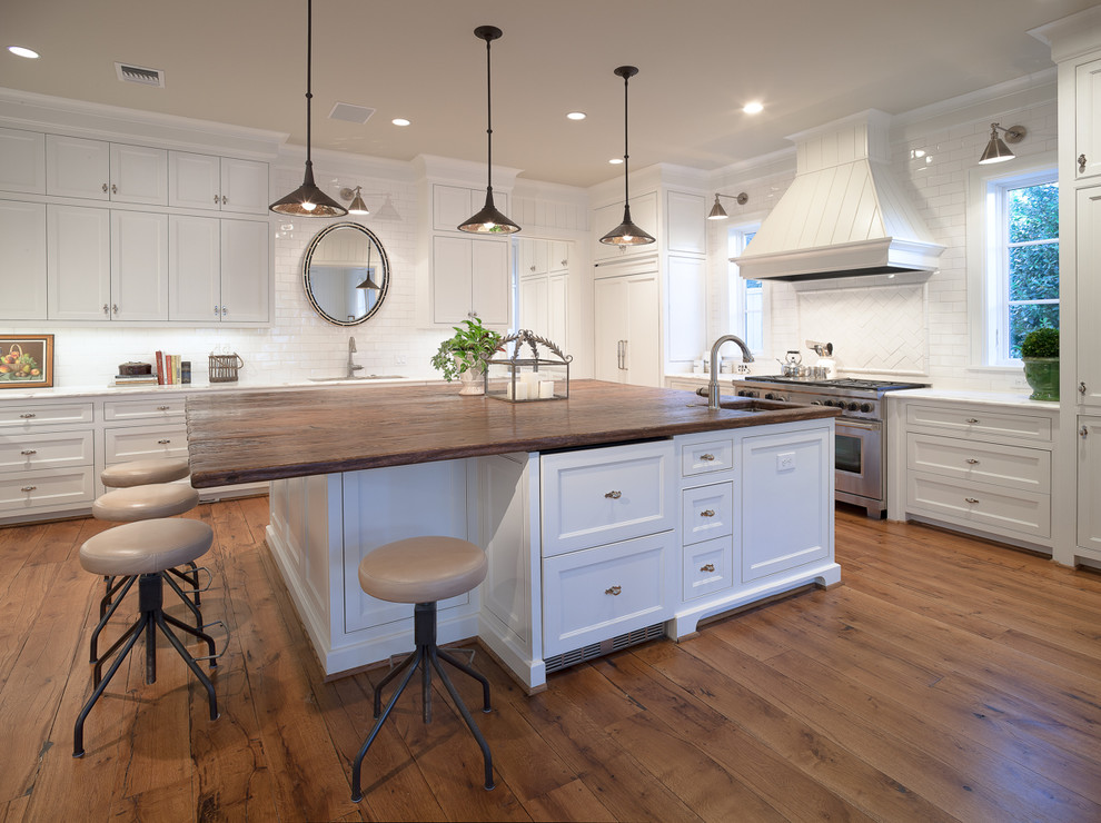 Traditional kitchen in Houston with recessed-panel cabinets, white cabinets, wood benchtops, white splashback, subway tile splashback and panelled appliances.