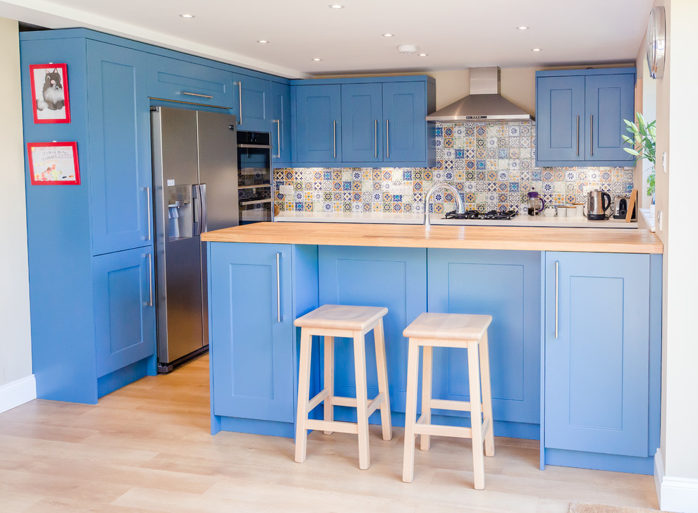 Design ideas for a mid-sized contemporary u-shaped eat-in kitchen in London with an undermount sink, shaker cabinets, blue cabinets, quartz benchtops, blue splashback, mosaic tile splashback, stainless steel appliances, laminate floors, a peninsula and beige floor.