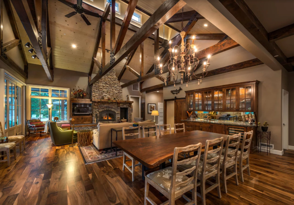 Photo of a large country open plan dining in Other with brown walls, dark hardwood floors, a standard fireplace, a stone fireplace surround and brown floor.