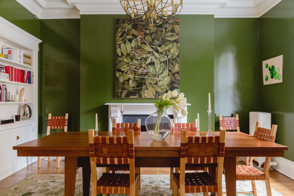 Tropical dining room in Chicago with green walls, light hardwood floors and a standard fireplace.