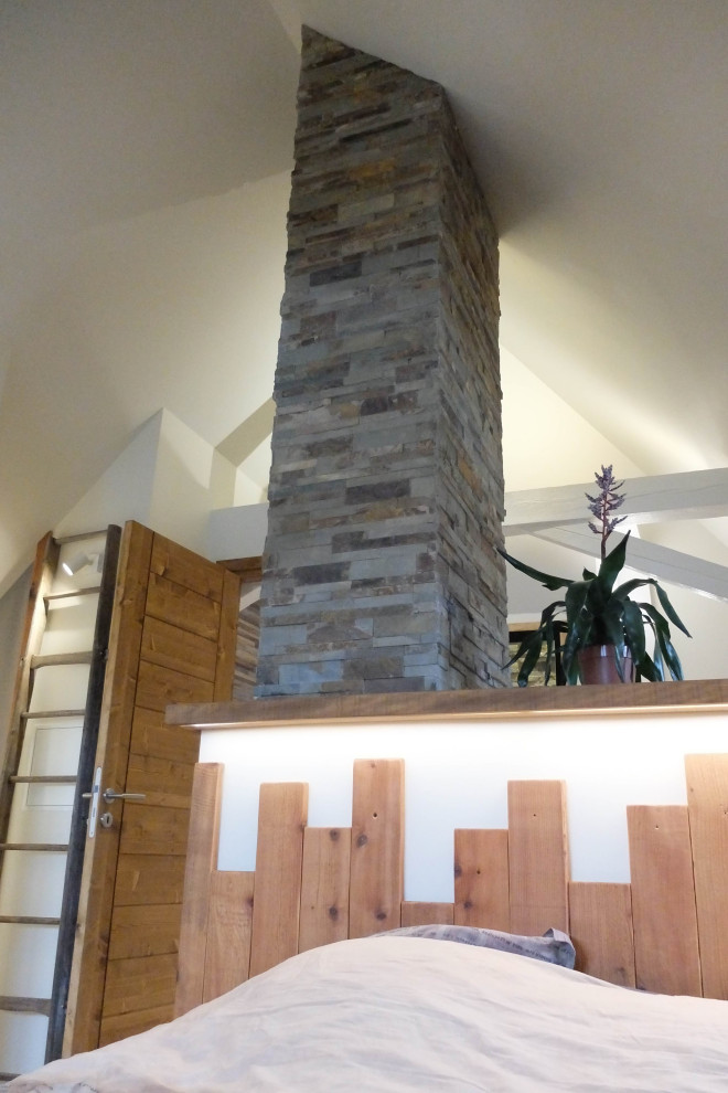 Idée de décoration pour une chambre minimaliste avec un manteau de cheminée en pierre de parement et poutres apparentes.