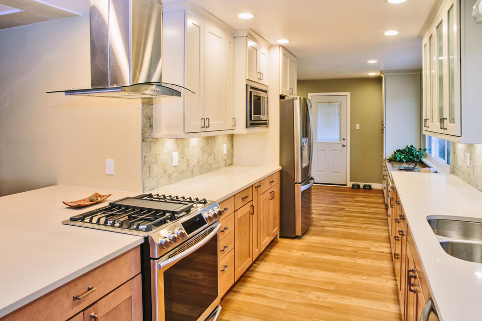 Inspiration for a large transitional galley eat-in kitchen in Denver with an undermount sink, shaker cabinets, light wood cabinets, quartz benchtops, green splashback, ceramic splashback, stainless steel appliances, laminate floors and a peninsula.