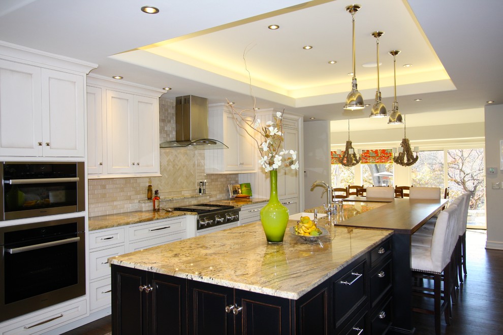 Inspiration for a large transitional single-wall dark wood floor and brown floor open concept kitchen remodel in Kansas City with a farmhouse sink, recessed-panel cabinets, white cabinets, granite countertops, beige backsplash, paneled appliances, an island and multicolored countertops