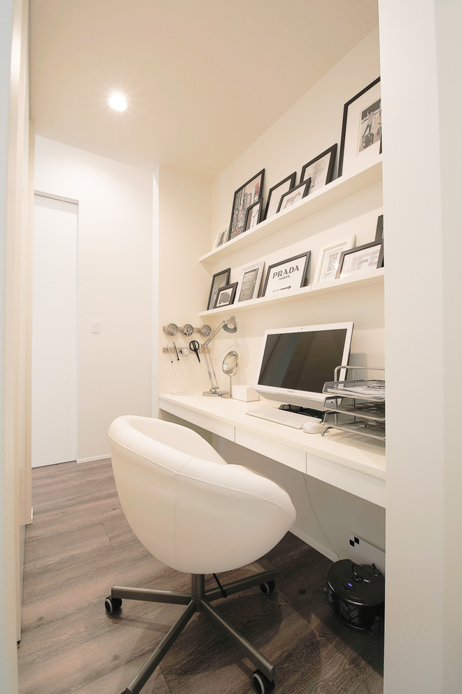 Photo of a small modern home office in Other with white walls, painted wood floors, a built-in desk and grey floor.