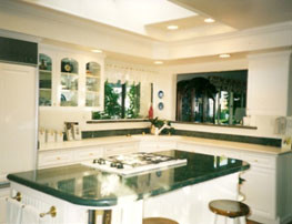 Example of a mid-sized classic u-shaped medium tone wood floor eat-in kitchen design in Orange County with an integrated sink, raised-panel cabinets, white cabinets, granite countertops, stone tile backsplash, white appliances and an island