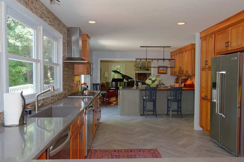 Photo of an expansive arts and crafts u-shaped eat-in kitchen in Seattle with an integrated sink, shaker cabinets, medium wood cabinets, solid surface benchtops, green splashback, stone tile splashback, stainless steel appliances, porcelain floors and with island.