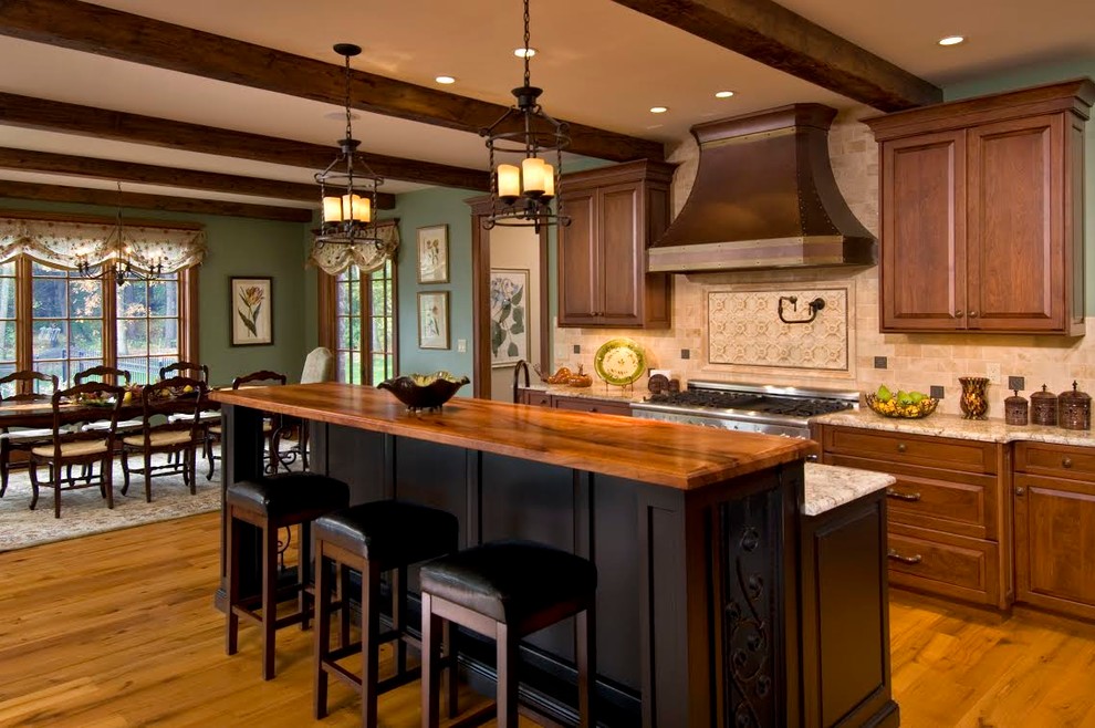 Design ideas for a large country single-wall eat-in kitchen in Boston with raised-panel cabinets, dark wood cabinets, granite benchtops, brown splashback, travertine splashback, dark hardwood floors, with island, brown floor and multi-coloured benchtop.