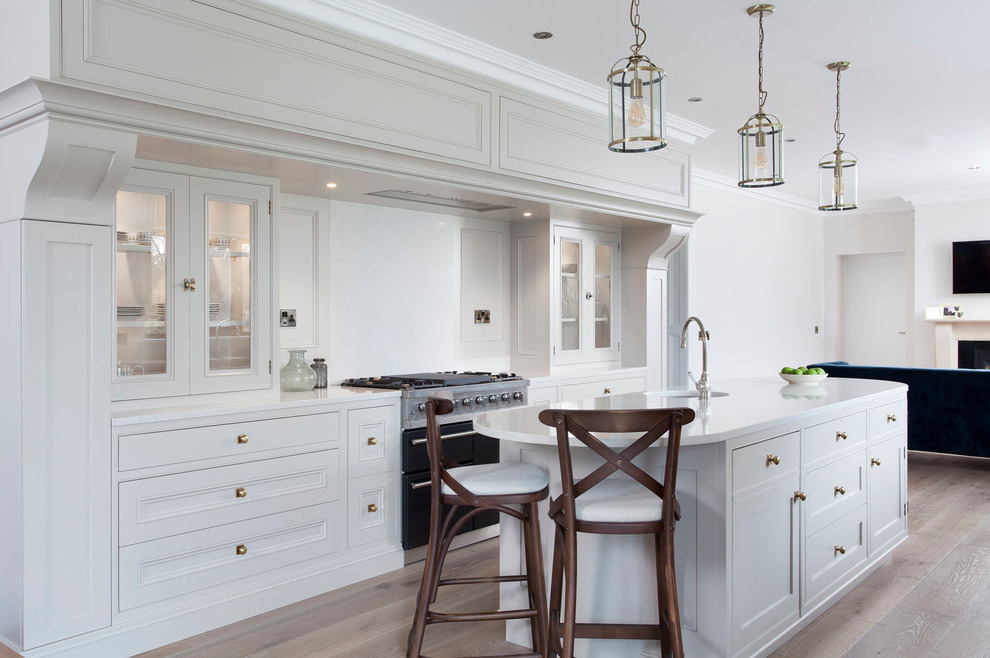 Photo of a transitional open plan kitchen in Dublin with recessed-panel cabinets, white cabinets and with island.