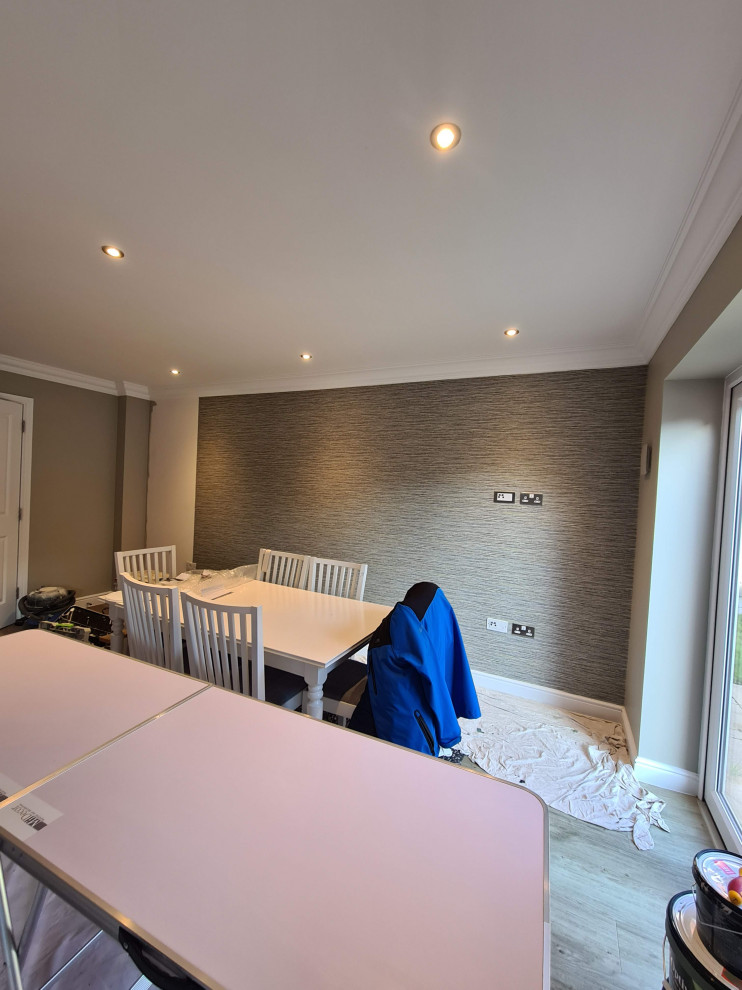 Idée de décoration pour une grande salle à manger ouverte sur le salon minimaliste avec un mur vert, sol en stratifié et un sol marron.