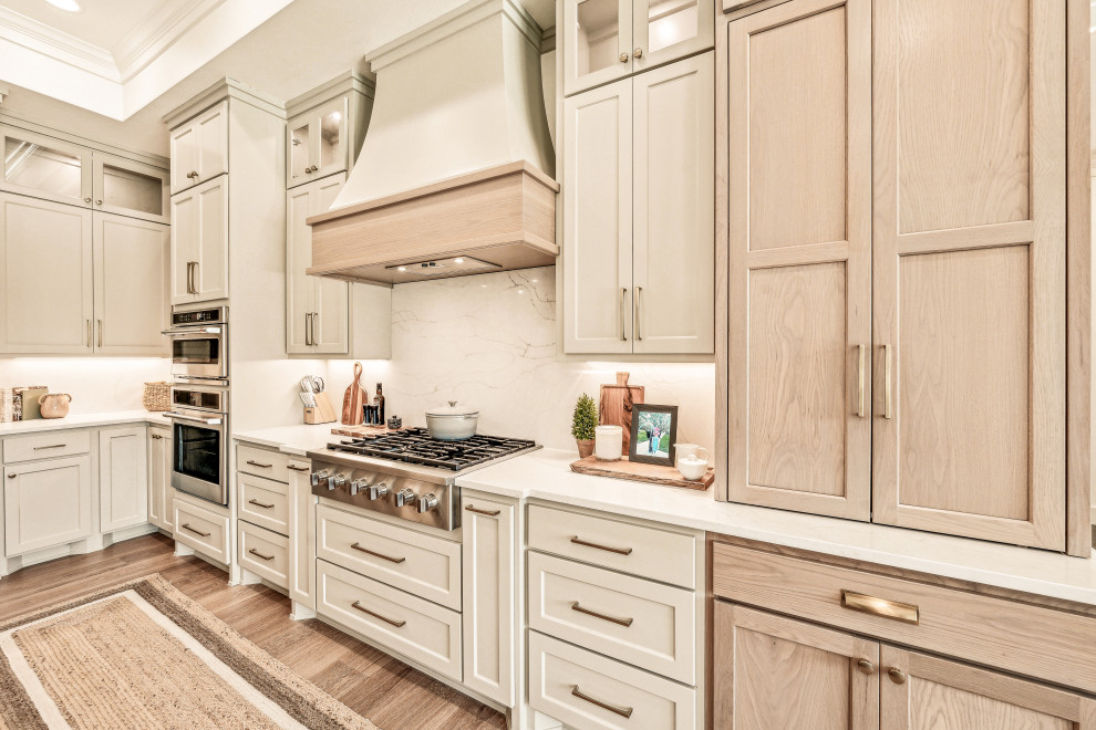 Mid-sized transitional l-shaped vinyl floor and tray ceiling eat-in kitchen photo in Dallas with an undermount sink, shaker cabinets, light wood cabinets, quartz countertops, white backsplash, quartz backsplash, stainless steel appliances, an island and white countertops
