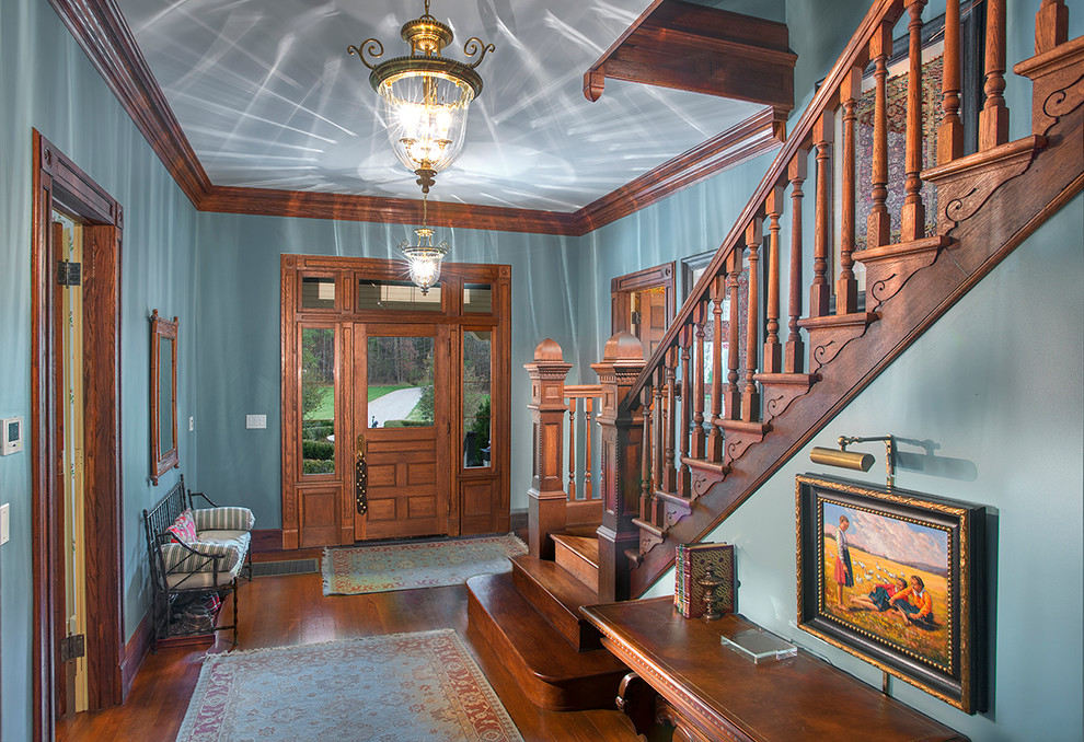 This is an example of a traditional foyer in Raleigh with blue walls, medium hardwood floors, a single front door and a medium wood front door.