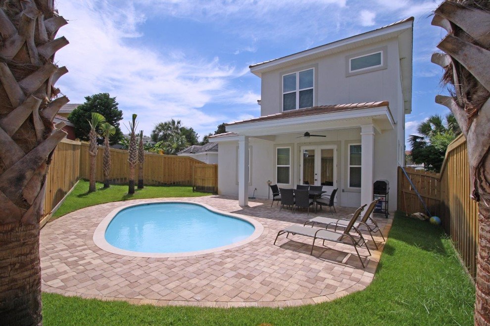 This is an example of a small beach style backyard kidney-shaped pool in Miami with natural stone pavers.