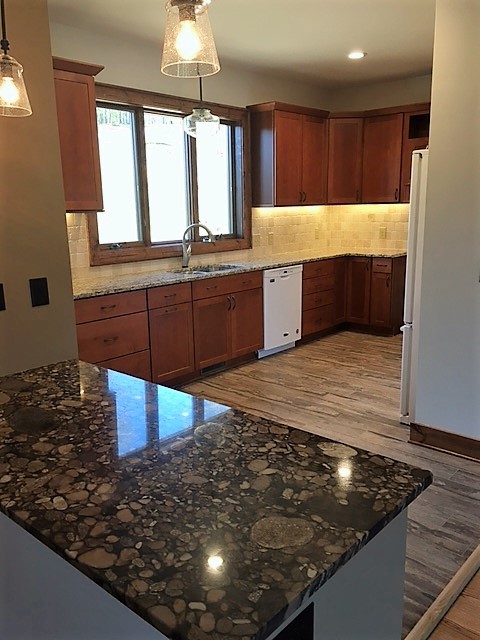 Example of a porcelain tile kitchen design in Charlotte with granite countertops and travertine backsplash