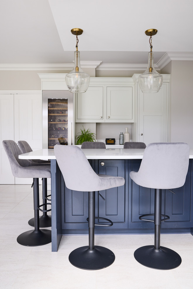 This is an example of a large contemporary u-shaped eat-in kitchen in Essex with a farmhouse sink, shaker cabinets, grey cabinets, granite benchtops, white splashback, granite splashback, stainless steel appliances, porcelain floors, with island, grey floor, white benchtop and coffered.