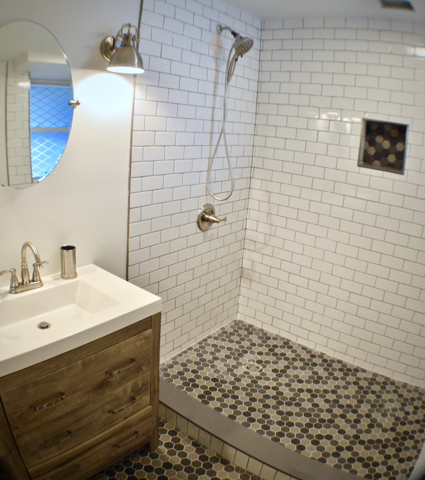 This is an example of a small beach style 3/4 bathroom in Portland Maine with recessed-panel cabinets, light wood cabinets, an open shower, a one-piece toilet, white tile, subway tile, white walls, porcelain floors, a wall-mount sink, multi-coloured floor, an open shower, white benchtops, a niche, a single vanity and a freestanding vanity.