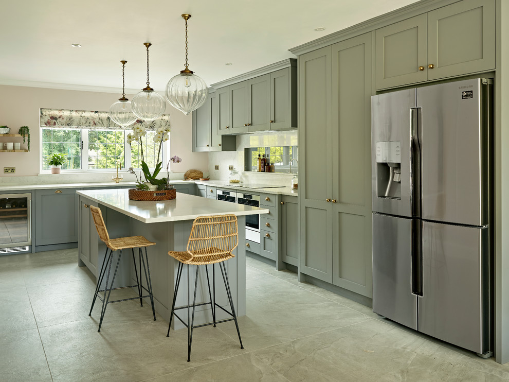 Inspiration for a transitional l-shaped kitchen in Surrey with shaker cabinets, grey cabinets, white splashback, stainless steel appliances, with island, grey floor and white benchtop.