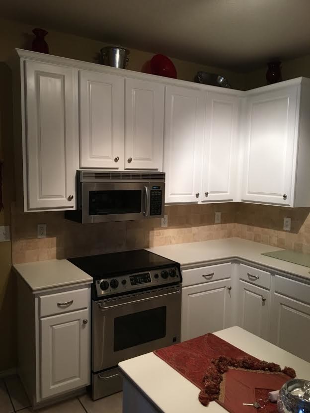 Enclosed kitchen - mid-sized transitional l-shaped enclosed kitchen idea with an integrated sink, raised-panel cabinets, white cabinets, laminate countertops, beige backsplash, porcelain backsplash, stainless steel appliances, an island and white countertops