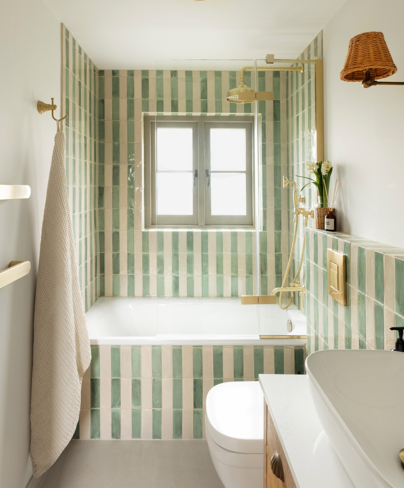 Photo of a small eclectic kids bathroom in Cornwall with white cabinets, a drop-in tub, a shower/bathtub combo, a wall-mount toilet, green tile, ceramic tile, green walls, ceramic floors, quartzite benchtops, grey floor, a hinged shower door, white benchtops, a single vanity and a freestanding vanity.