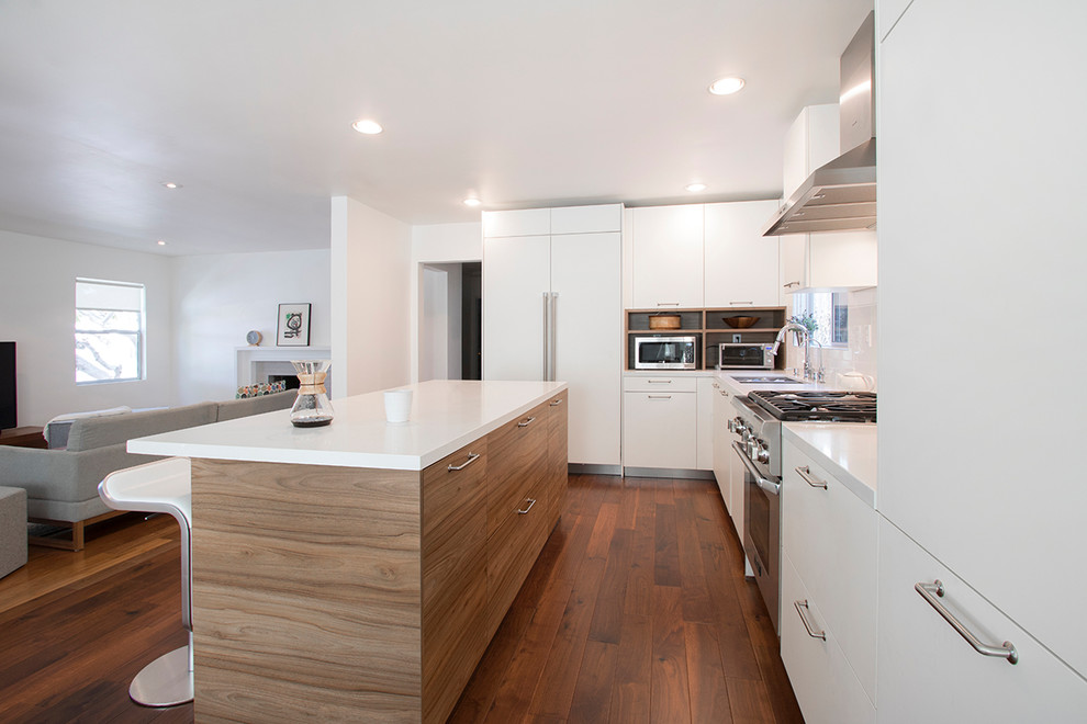 Photo of a mid-sized contemporary l-shaped eat-in kitchen in Los Angeles with a drop-in sink, flat-panel cabinets, medium wood cabinets, quartzite benchtops, white splashback, porcelain splashback, stainless steel appliances, laminate floors, with island, brown floor and white benchtop.