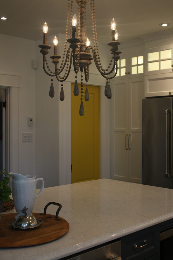 Example of a mid-sized transitional l-shaped kitchen design with shaker cabinets, white cabinets, white backsplash, stainless steel appliances, an island, a double-bowl sink and mosaic tile backsplash