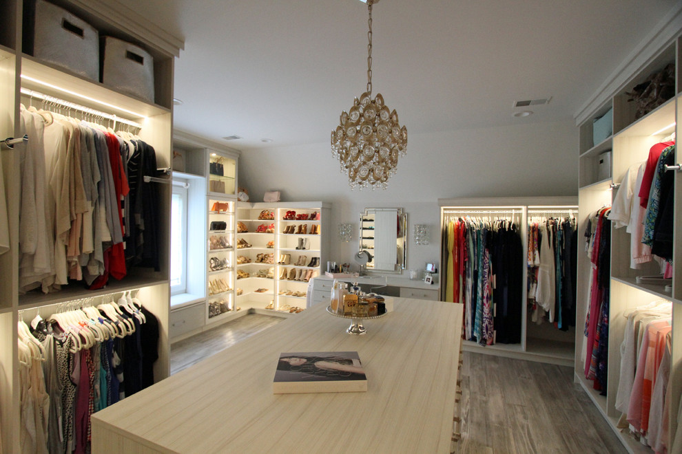 This is an example of a large transitional women's walk-in wardrobe in Detroit with glass-front cabinets, light wood cabinets, light hardwood floors and grey floor.