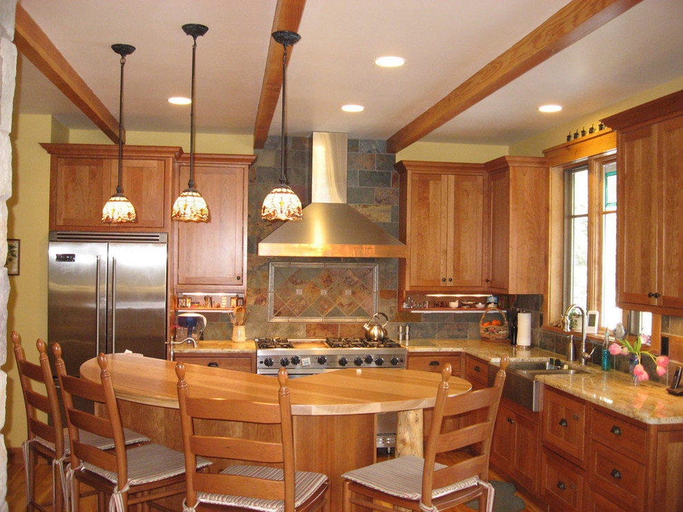 Photo of a mid-sized traditional l-shaped open plan kitchen in Albuquerque with a farmhouse sink, shaker cabinets, medium wood cabinets, granite benchtops, multi-coloured splashback, slate splashback, stainless steel appliances, medium hardwood floors, with island, brown floor and beige benchtop.