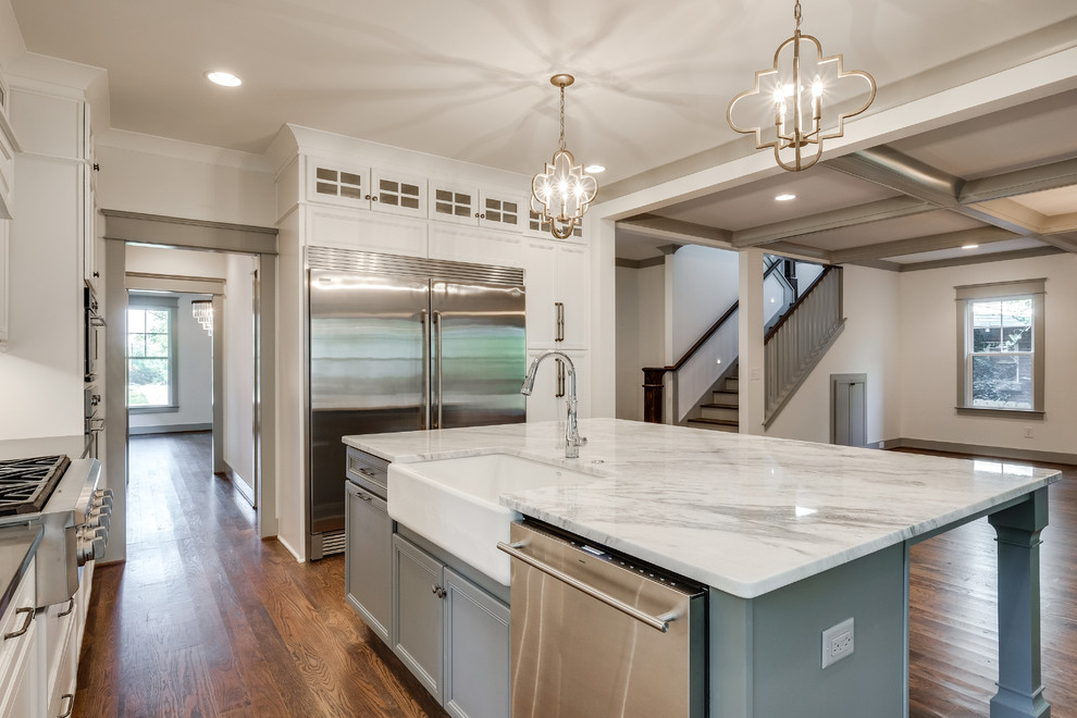 Inspiration for a large traditional l-shaped open plan kitchen in Nashville with with island, a farmhouse sink, recessed-panel cabinets, white cabinets, granite benchtops, white splashback, subway tile splashback, stainless steel appliances and medium hardwood floors.