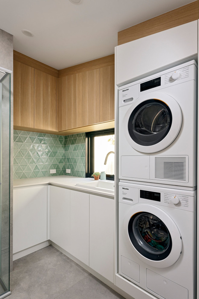 This is an example of a mid-sized scandinavian l-shaped utility room in Perth with a single-bowl sink, flat-panel cabinets, white cabinets, quartz benchtops, green splashback, mosaic tile splashback, white walls, porcelain floors, a stacked washer and dryer, grey floor, white benchtop and vaulted.