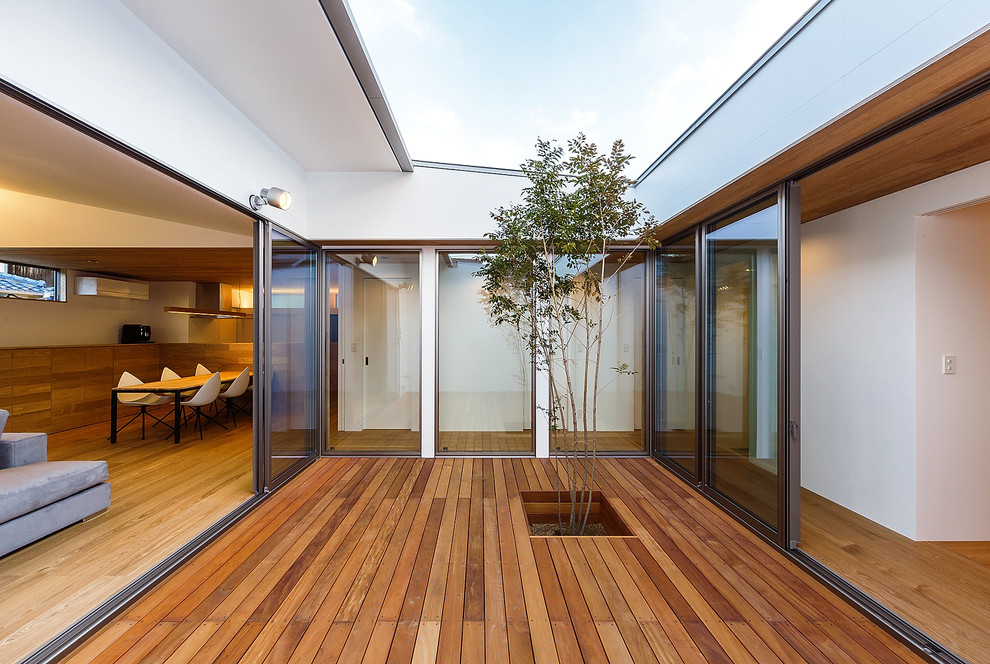 Photo of a mid-sized asian courtyard deck in Other with a roof extension.