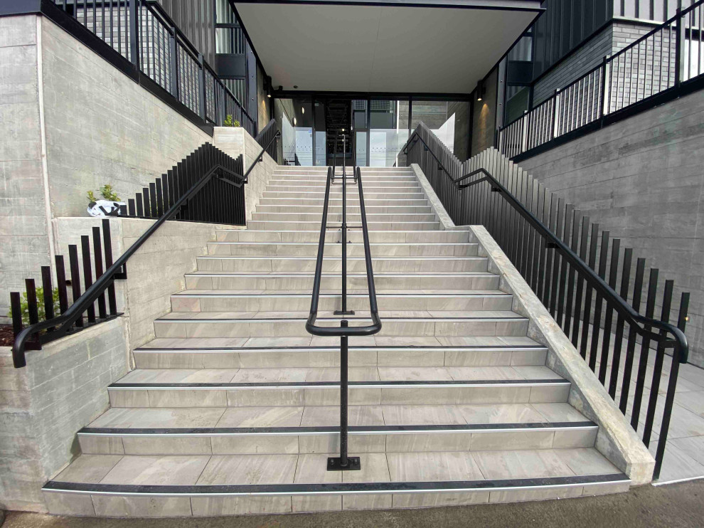 This is an example of a medium sized modern concrete straight metal railing staircase in Auckland with concrete risers.