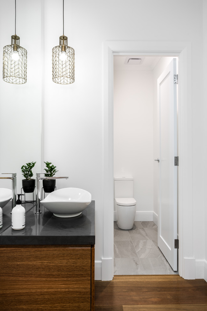 This is an example of a contemporary powder room in Adelaide with medium wood cabinets, medium hardwood floors, engineered quartz benchtops and brown floor.