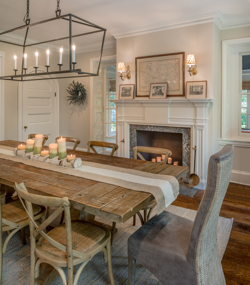 Large country dining room in Philadelphia with grey walls, medium hardwood floors, a standard fireplace, a stone fireplace surround and brown floor.
