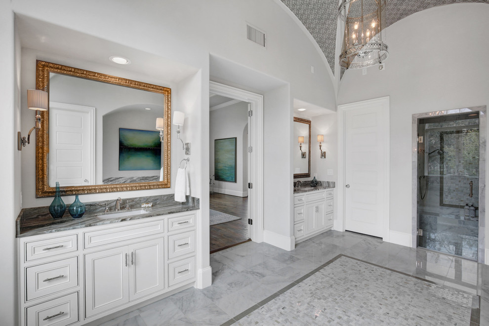 Large mediterranean master bathroom in Dallas with beaded inset cabinets, white cabinets, a drop-in tub, an alcove shower, gray tile, marble, grey walls, marble floors, an undermount sink, granite benchtops, white floor and a hinged shower door.